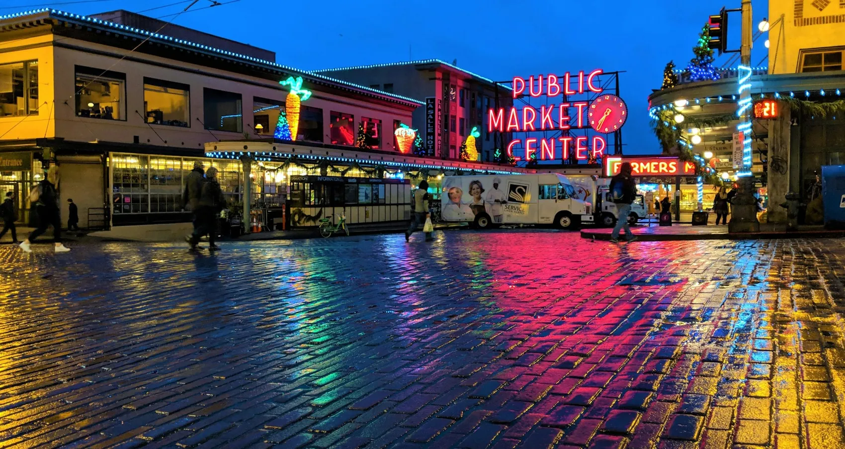 Pike Place Market in Seattle on a wet evening, neon signs reflected in the rain-soaked street